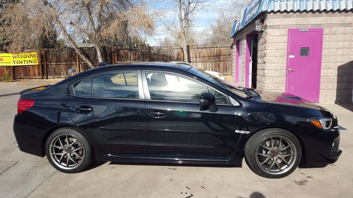 A black subaru wrx sti is parked in front of a purple door.