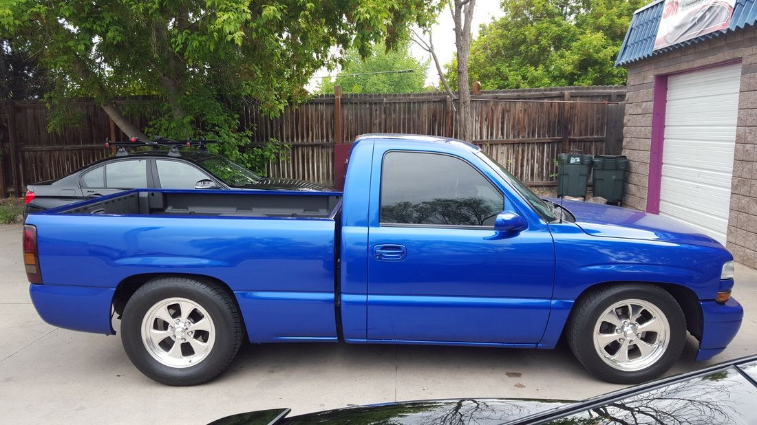 A blue truck is parked in front of a garage.