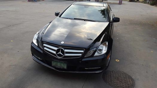 A black mercedes benz is parked in a parking lot.