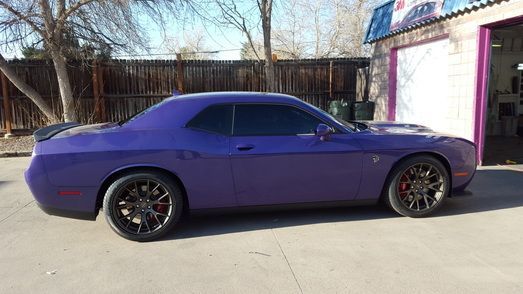 A purple dodge challenger is parked in front of a garage.