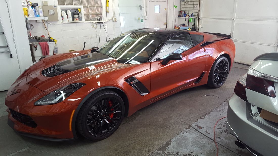 A red sports car is parked in a garage next to a silver car.