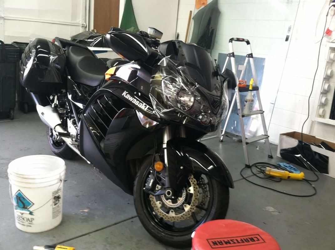 A black kawasaki motorcycle is parked in a garage