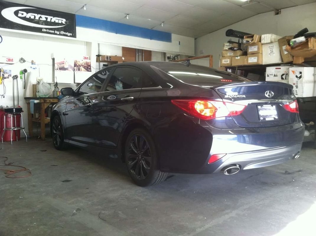 A black hyundai sonata is parked in a garage