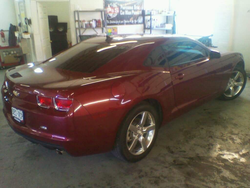 A red chevrolet camaro is parked in a garage