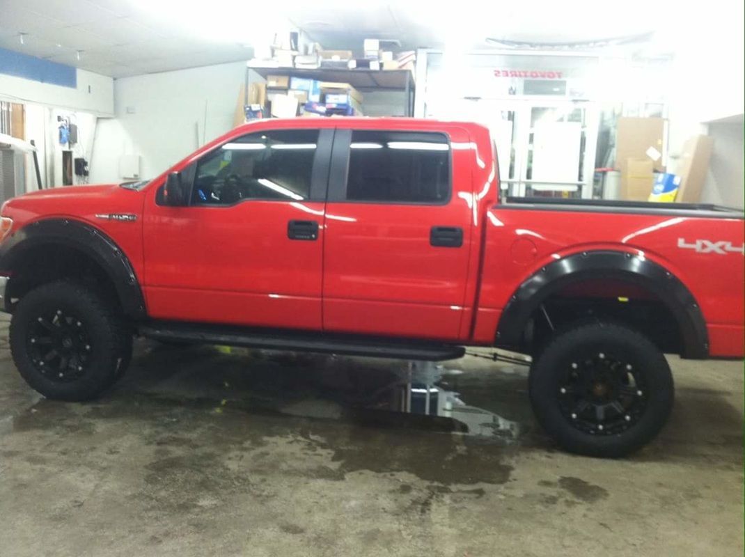 A red ford truck is parked in a garage