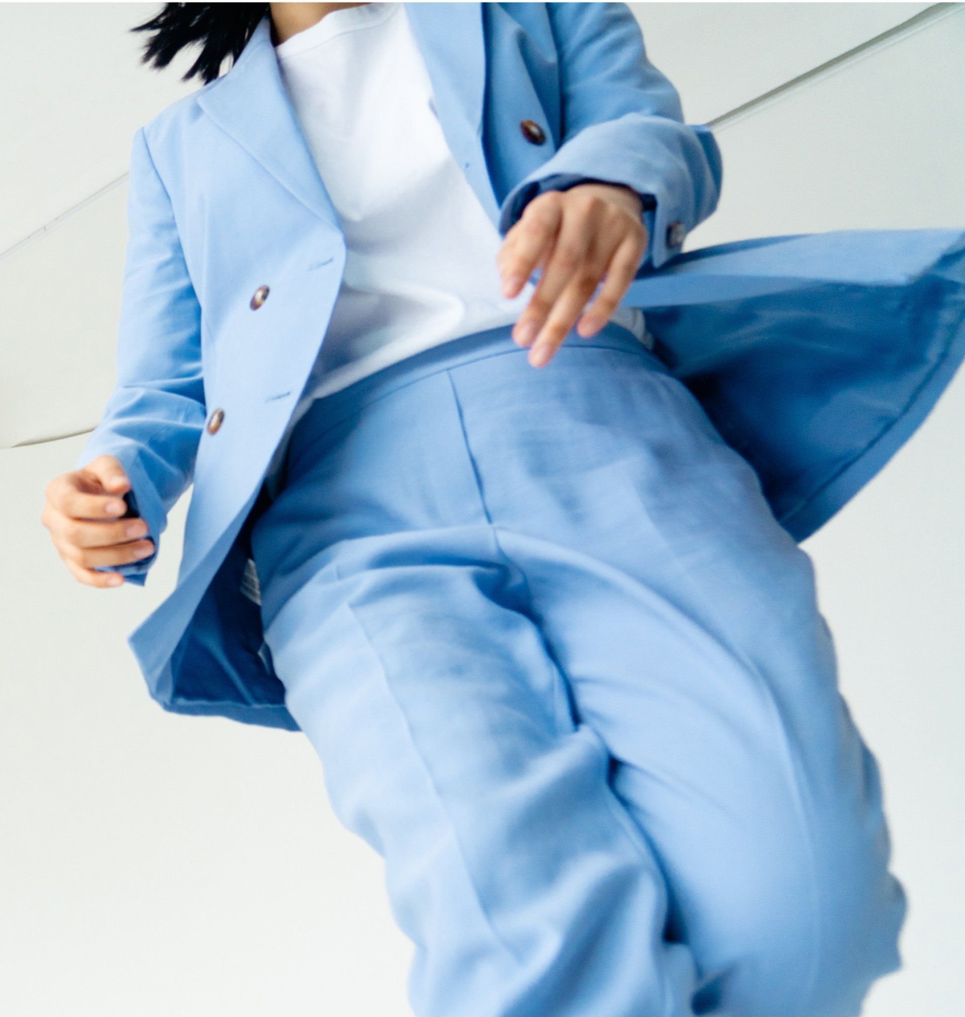 A woman is wearing a light blue suit and a white shirt.