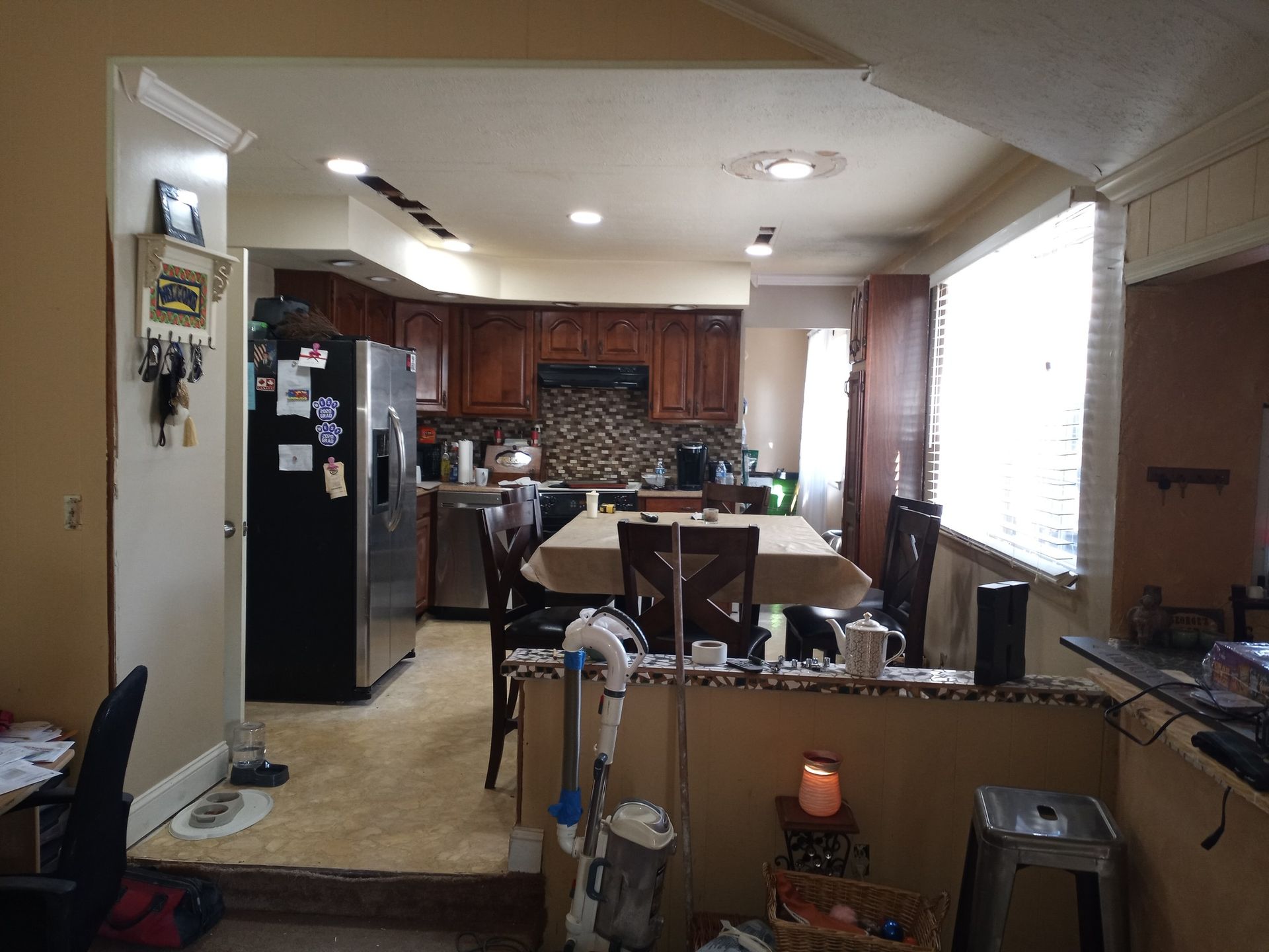 Open kitchen and dining area with dark wood cabinets, black refrigerator, and window blinds letting in bright light
