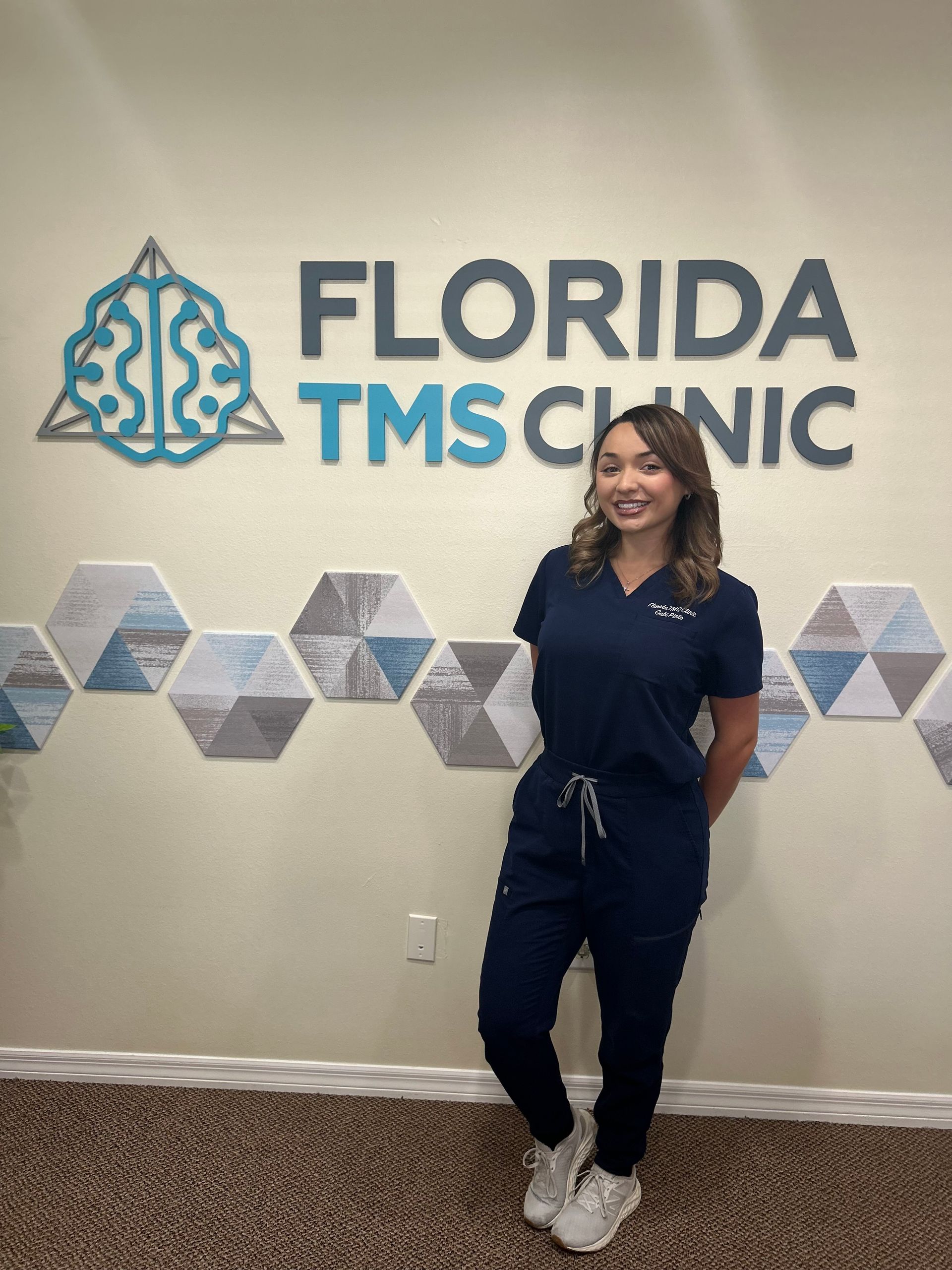 Woman in navy scrubs stands in front of