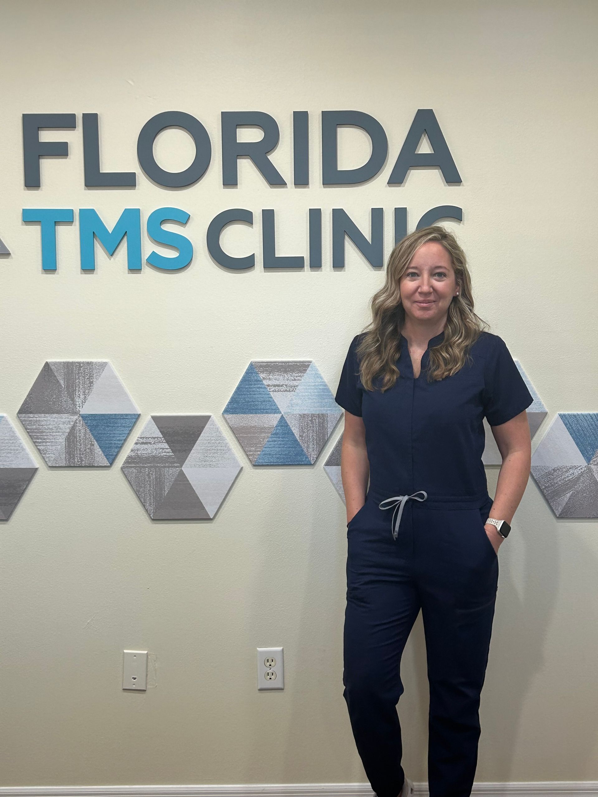Woman in navy scrubs stands in front of a