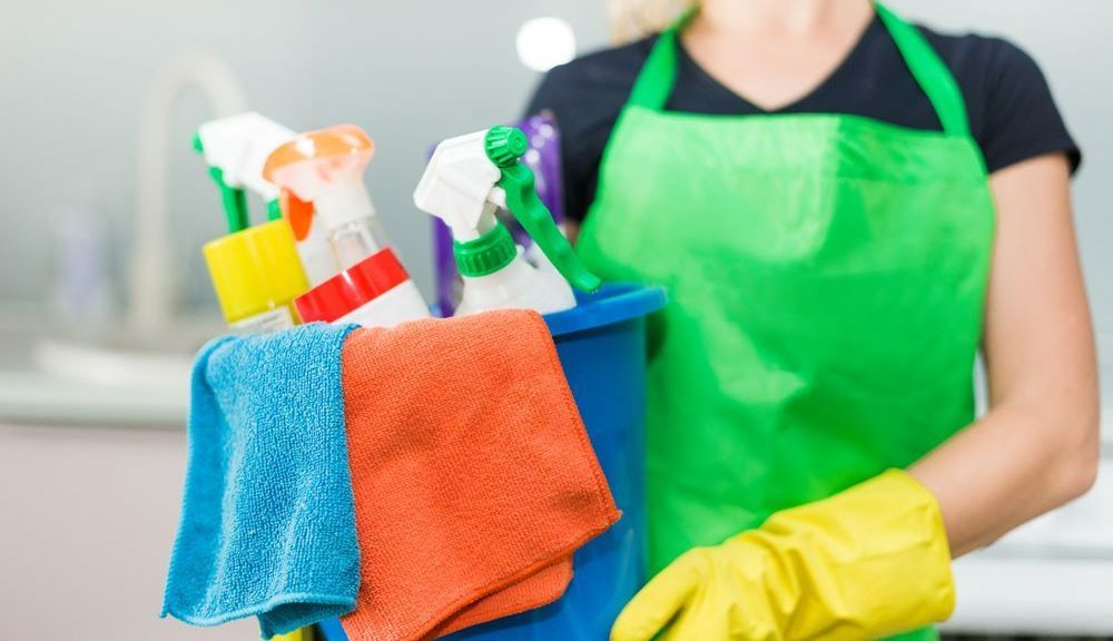 A Woman in Protective Suit Is Holding a Bucket of Cleaning Supplies — Mackay Cleaning & Packaging Supplies in Mackay, QLD