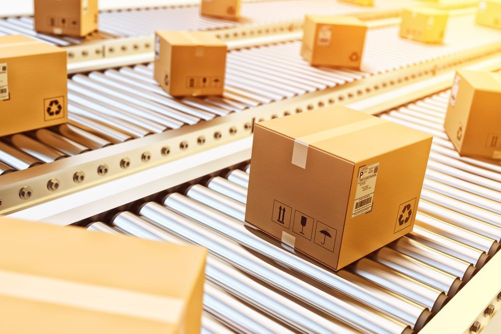 A Conveyor Belt Filled With Cardboard Boxes in a Factory — Mackay Cleaning & Packaging Supplies in Mackay, QLD