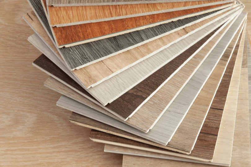 A fanned-out selection of wood-look flooring samples in various shades of brown, gray, and tan.