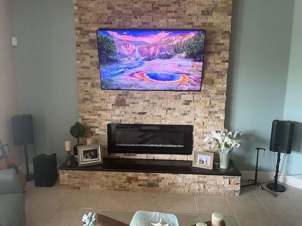 A living room with a fireplace and a flat screen tv on the wall.