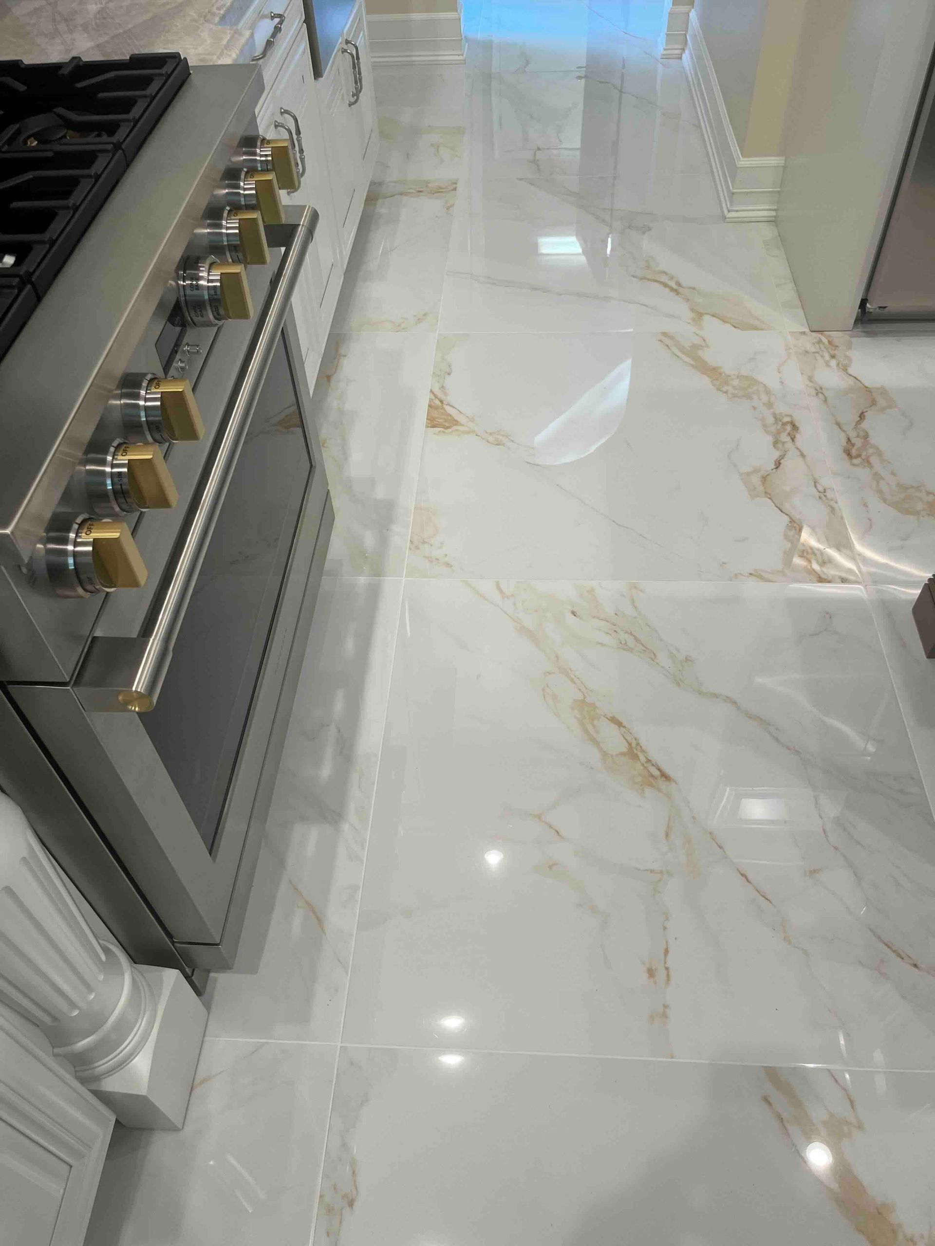 A kitchen with a stove and oven and a marble floor.