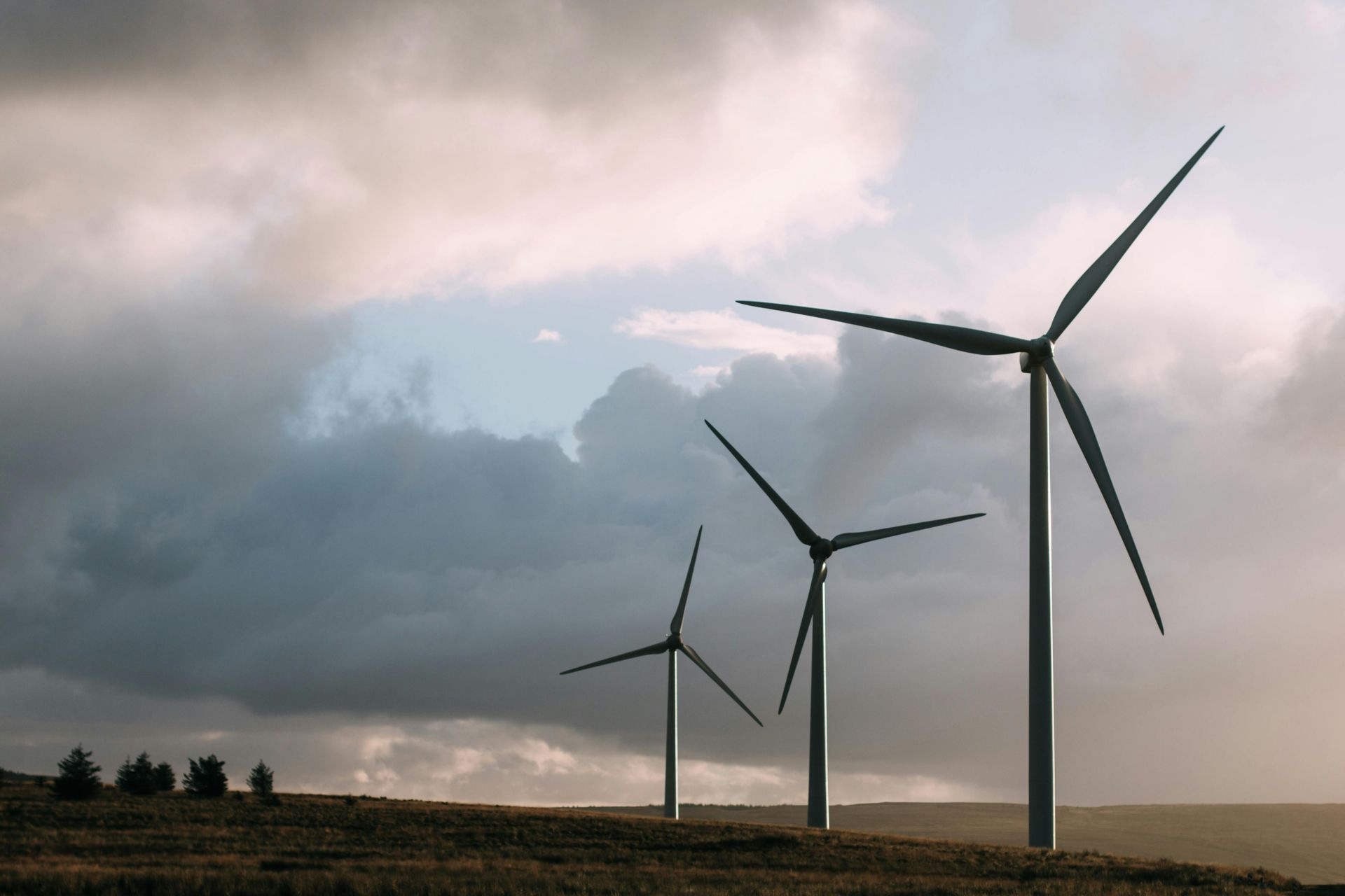 Three wind turbines are sitting on top of a hill.