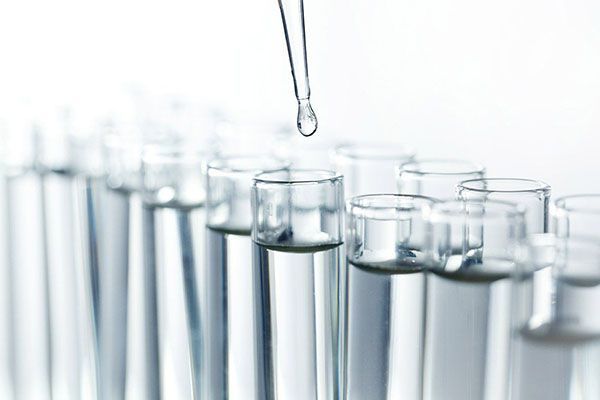A drop of liquid is being poured into a test tube.