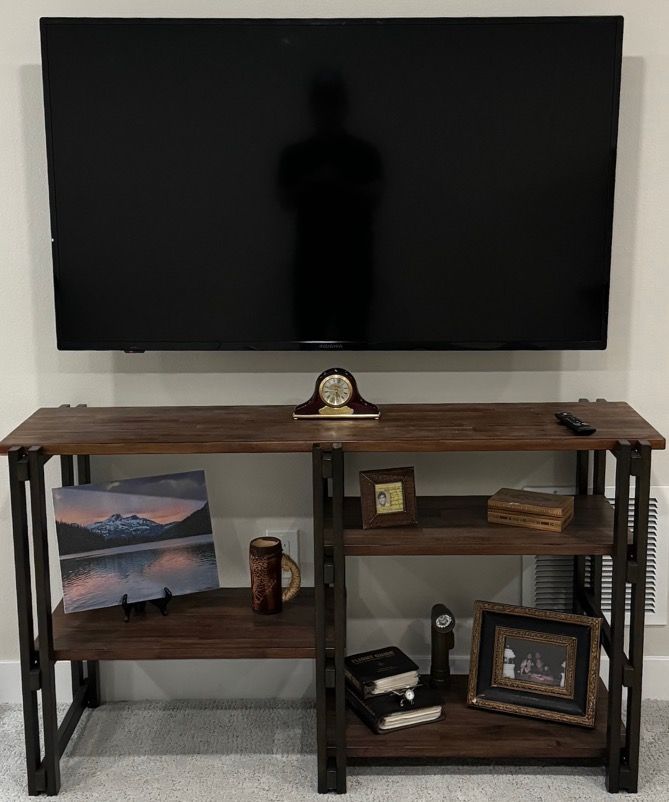 TV mounted above a brown console table with various decorative objects.