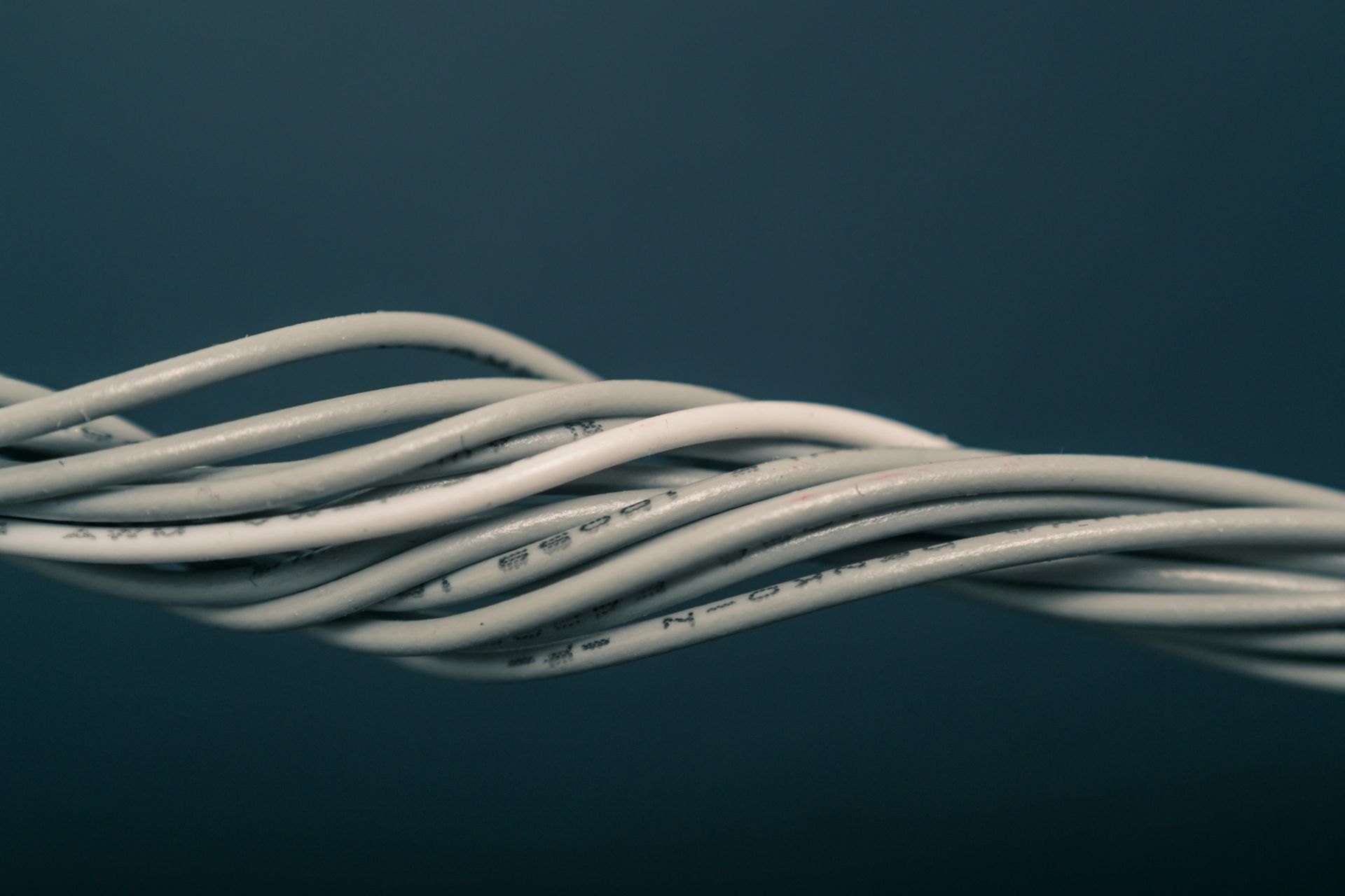 Twisted bundle of white wires against a dark blue background.