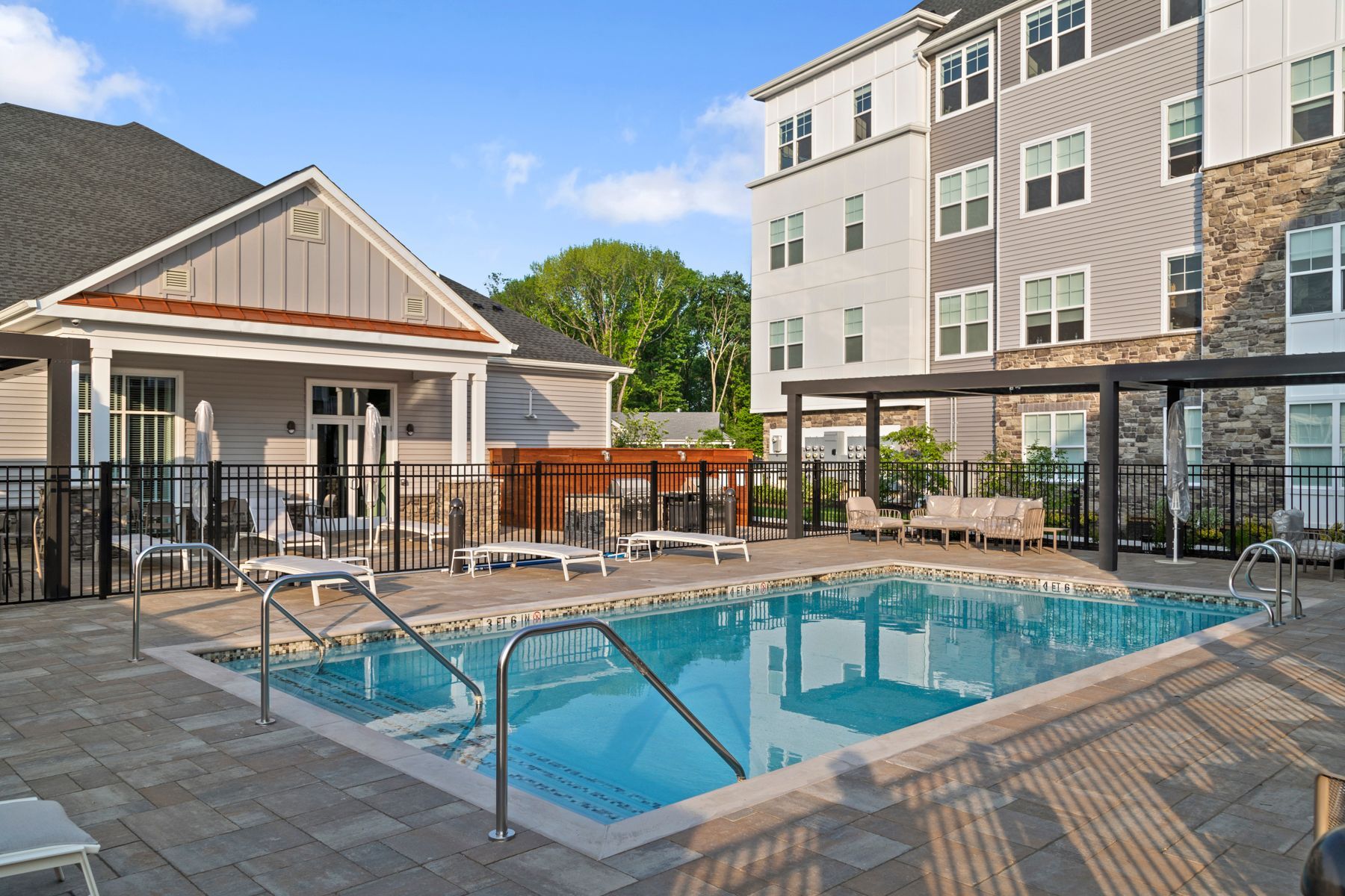 Pool area with a pool, lounge chairs, and an apartment building.