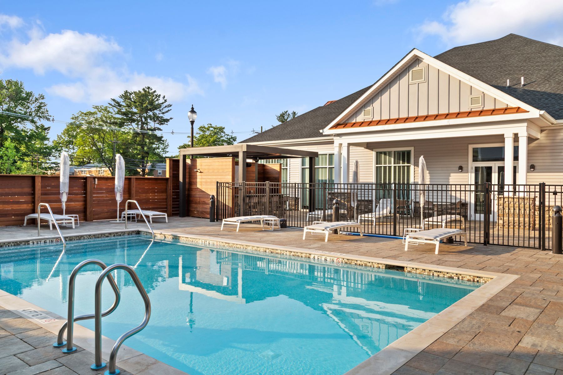 Pool with lounge chairs next to a building on a sunny day.