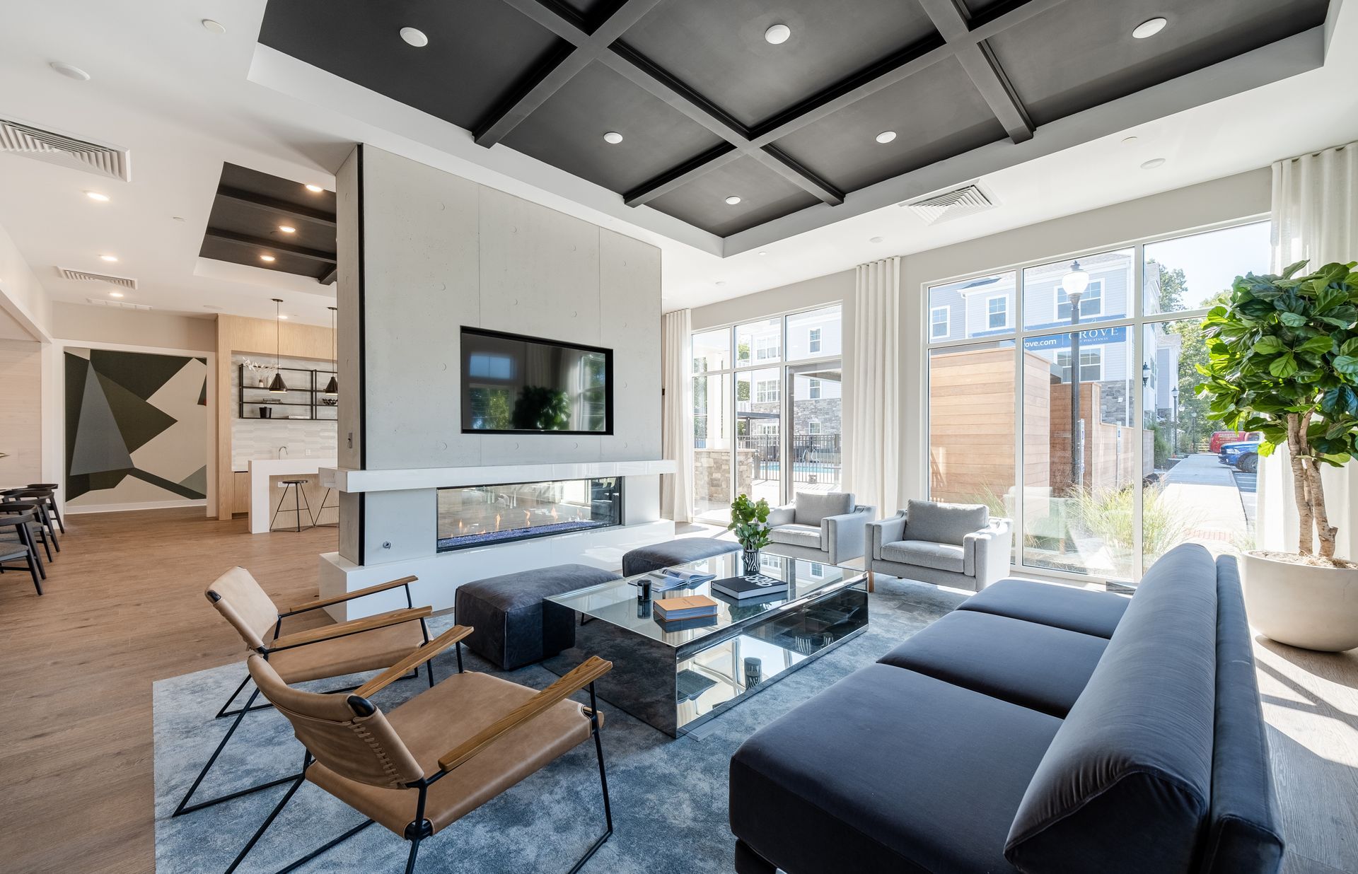 Modern living room with fireplace, TV, seating, and large windows. Black and gray decor.