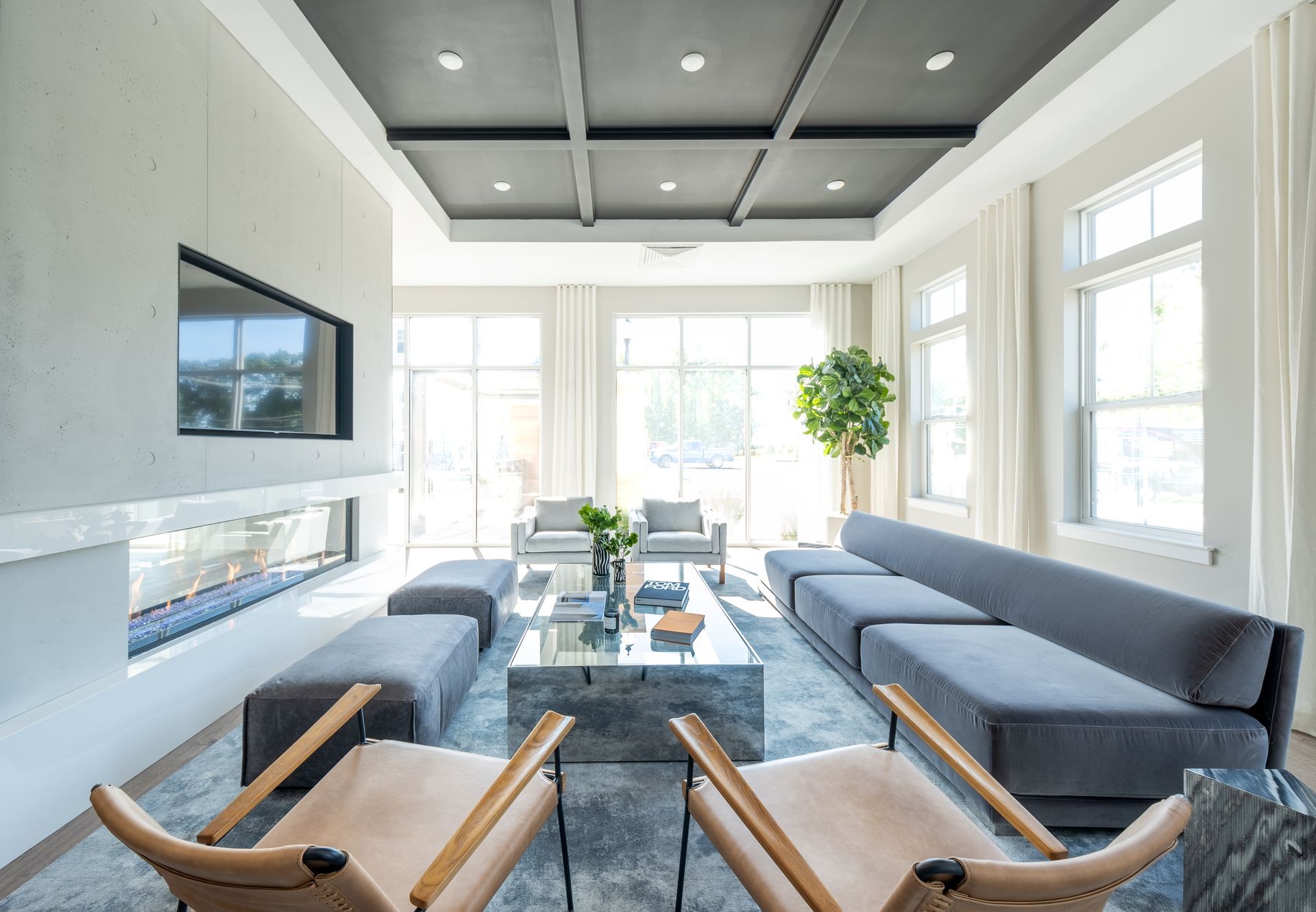 Modern living room with fireplace, gray sofa, and large windows.