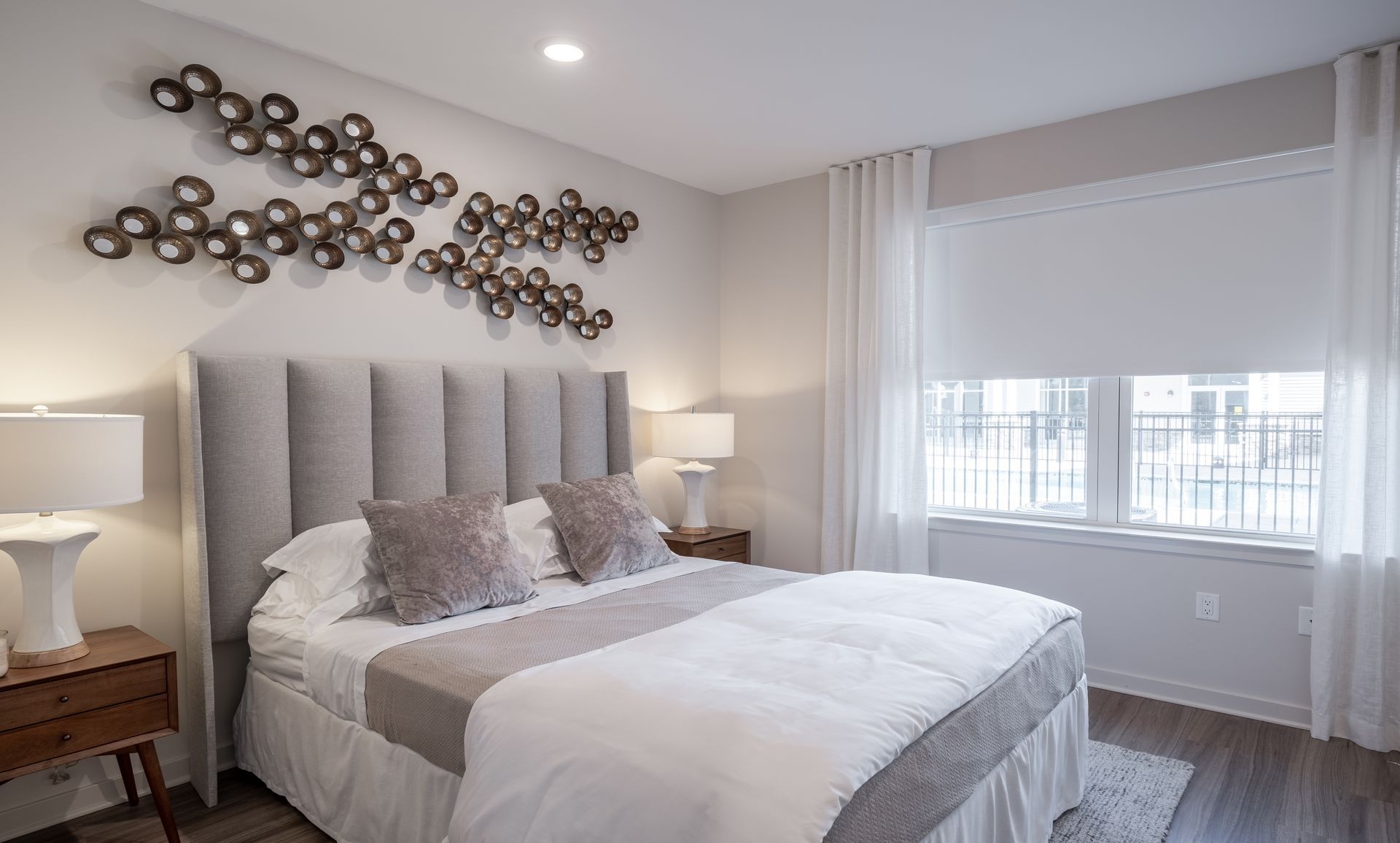 Bedroom with bed, neutral color scheme, headboard, decorative wall art, and window with curtains.
