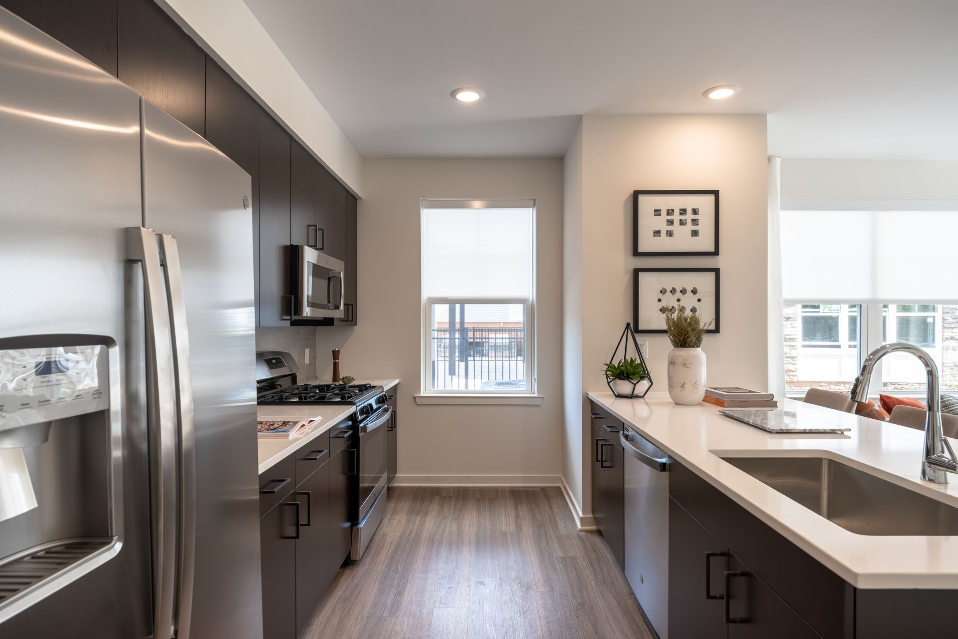 Modern kitchen with stainless steel appliances, dark cabinets, and white countertops.