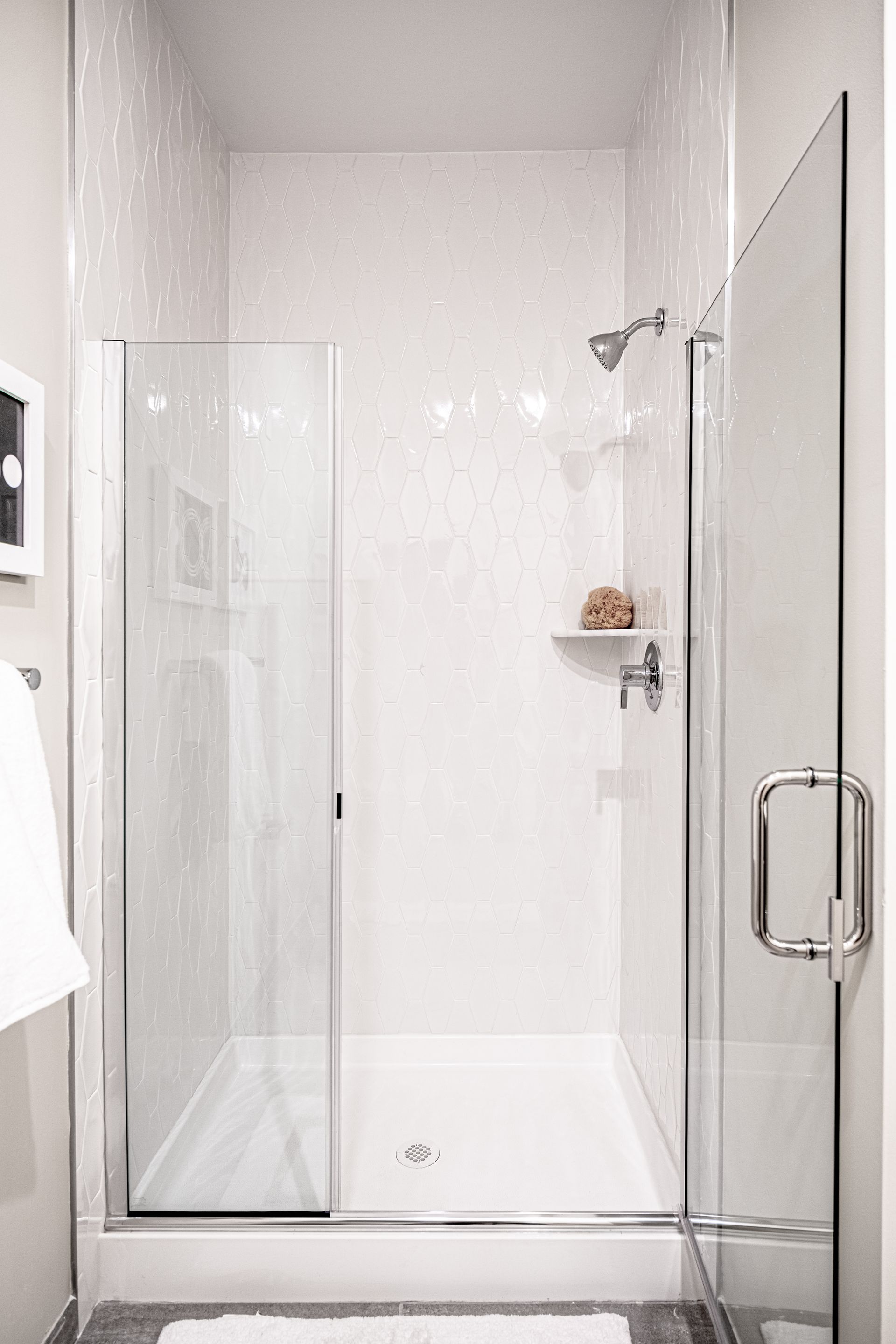 White modern shower stall with glass doors and a built-in shelf.