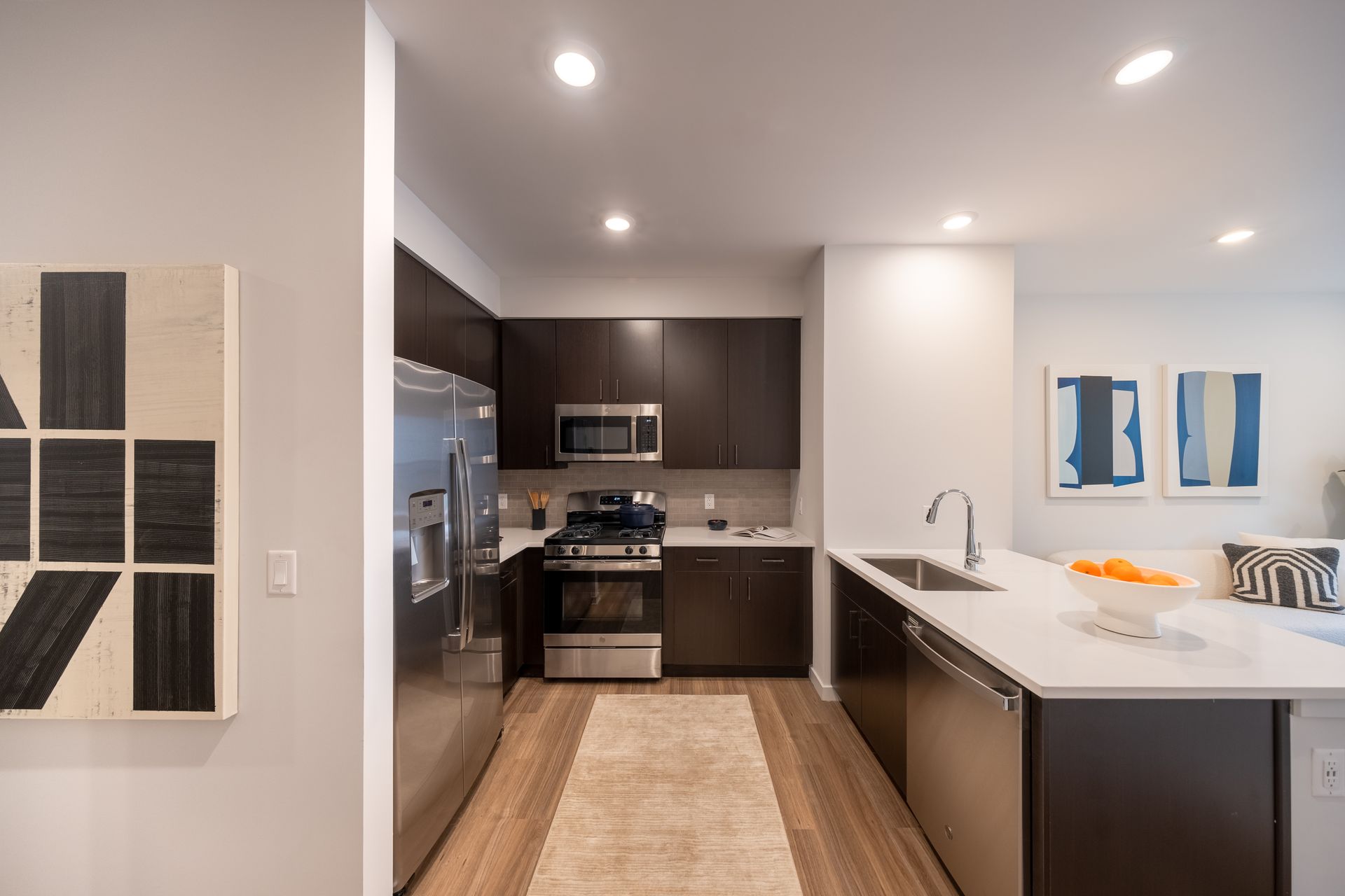 Modern kitchen with dark cabinetry, stainless steel appliances, and a white countertop island.