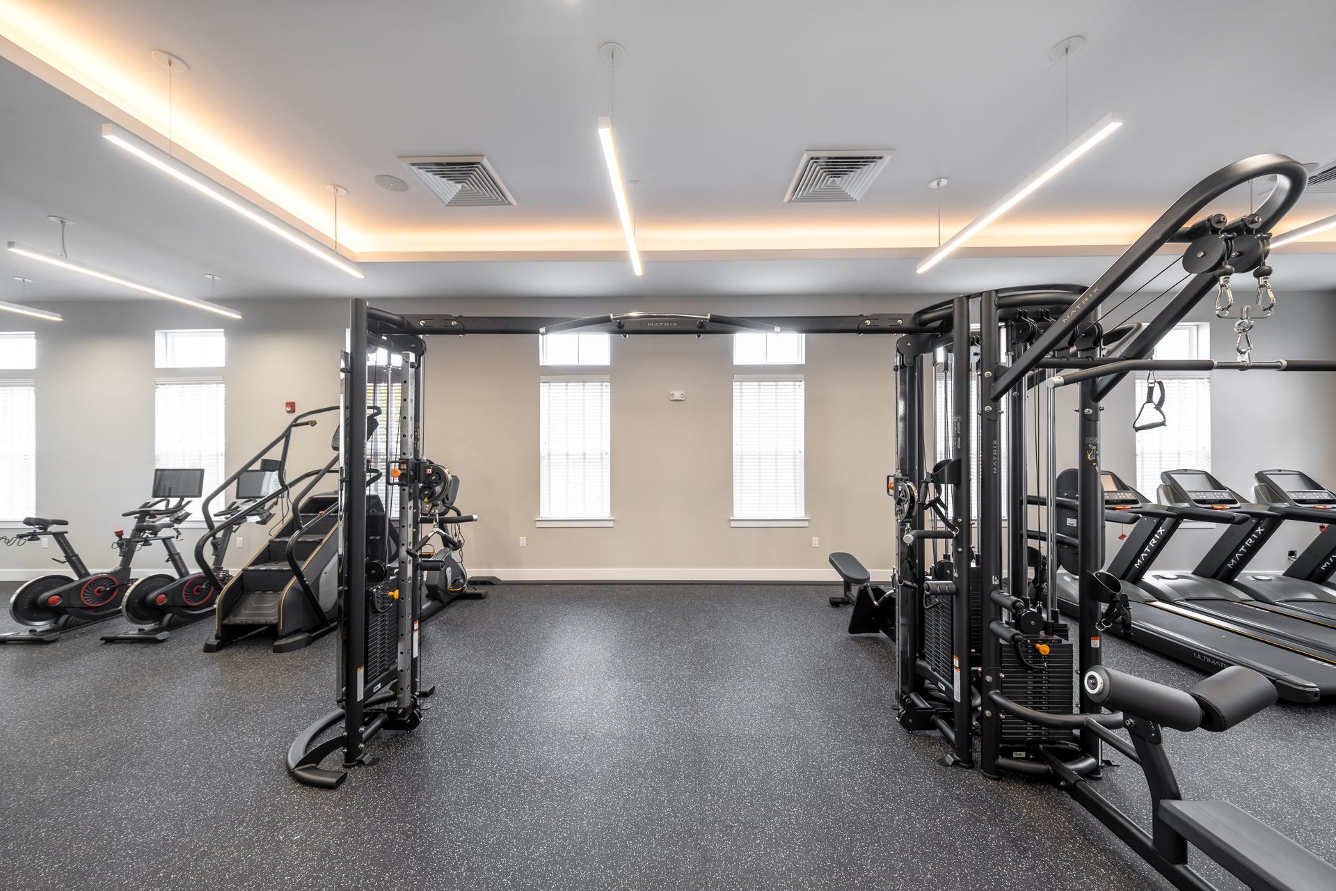 Gym with exercise equipment, including treadmills and weight machines, against neutral walls.
