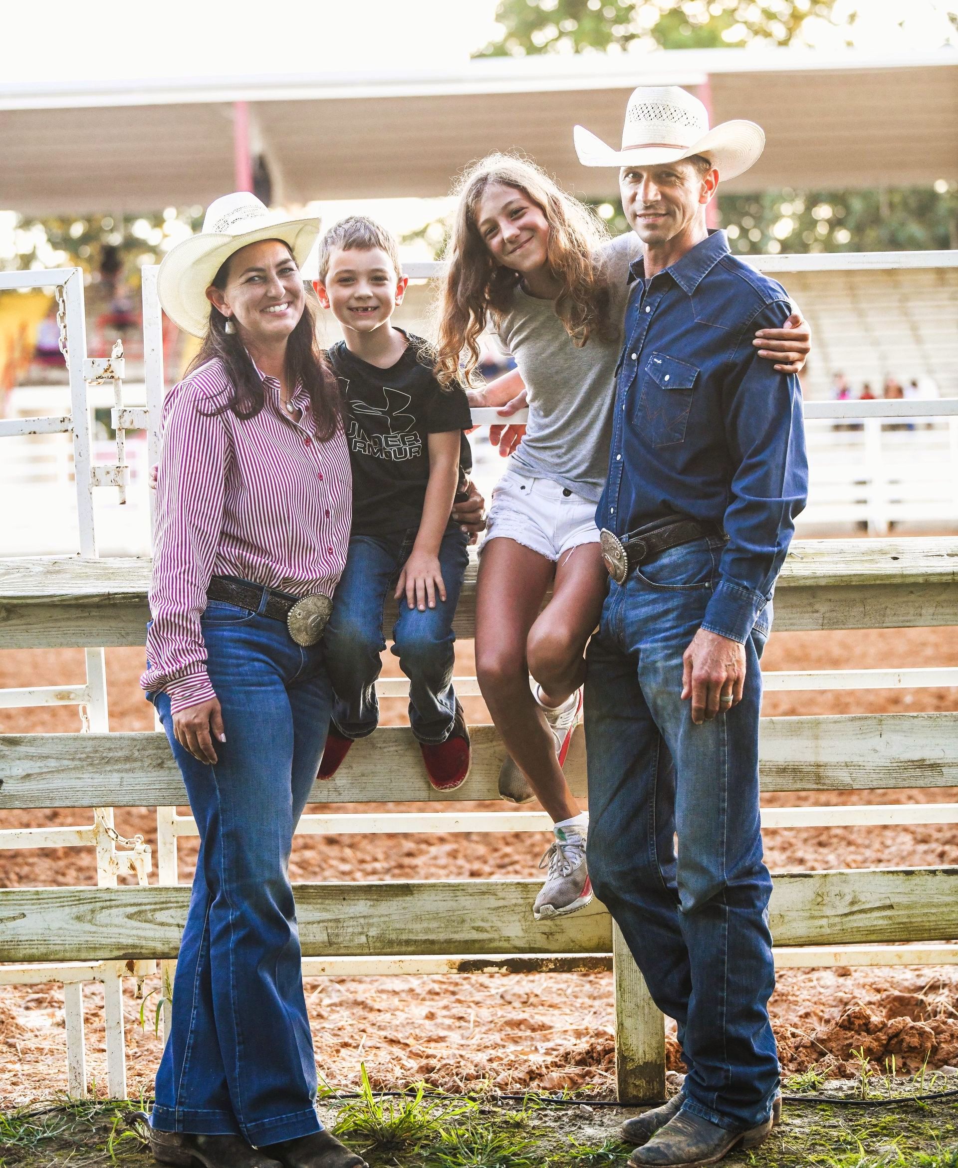 A family is posing for a picture while standing next to a wooden fence.