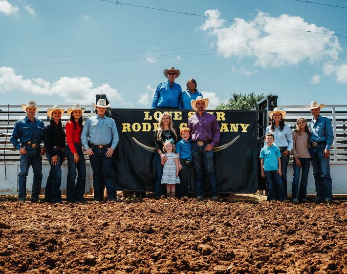 A group of people standing in front of a sign that says rodeo any