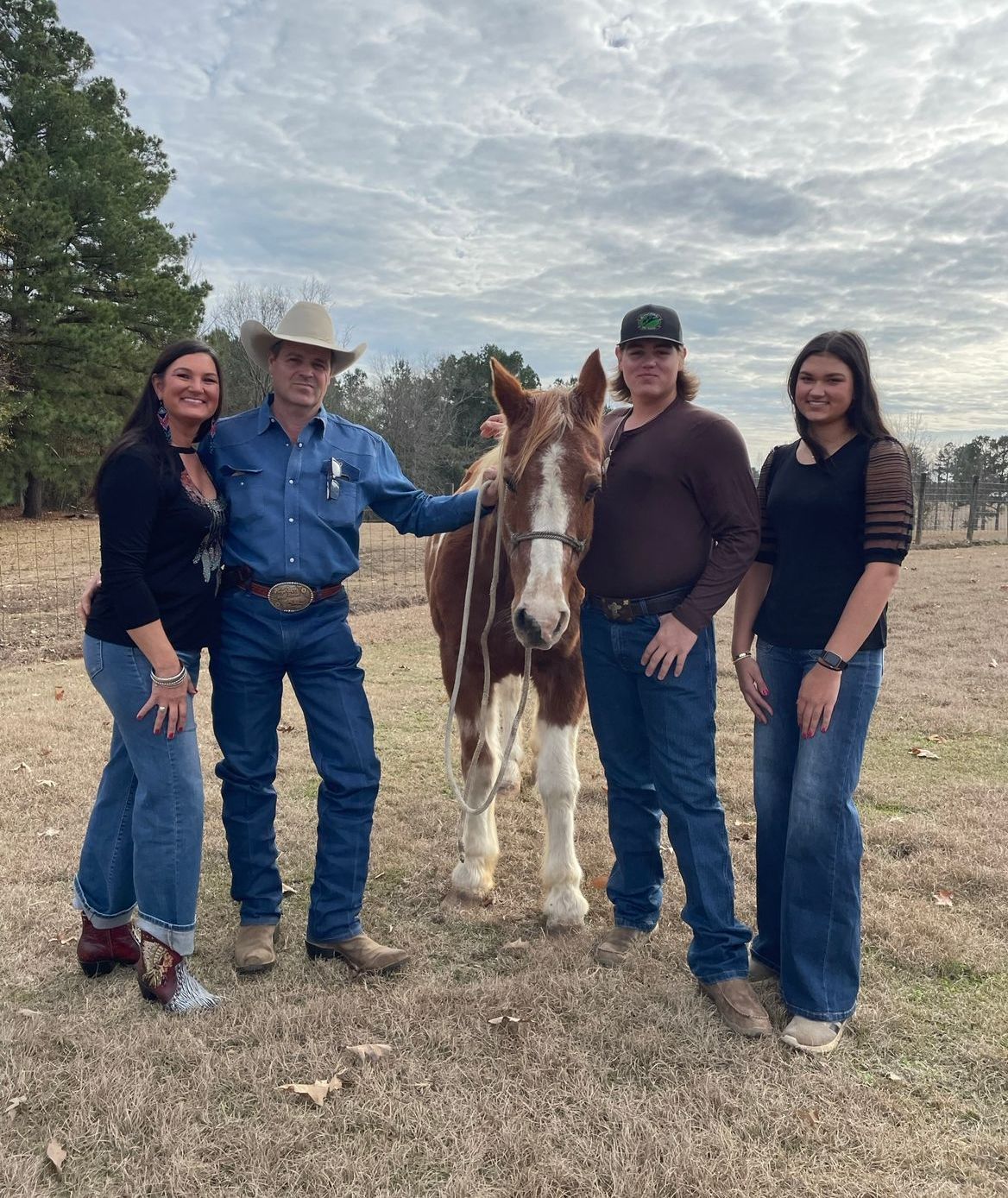 A group of people standing next to a horse in a field.