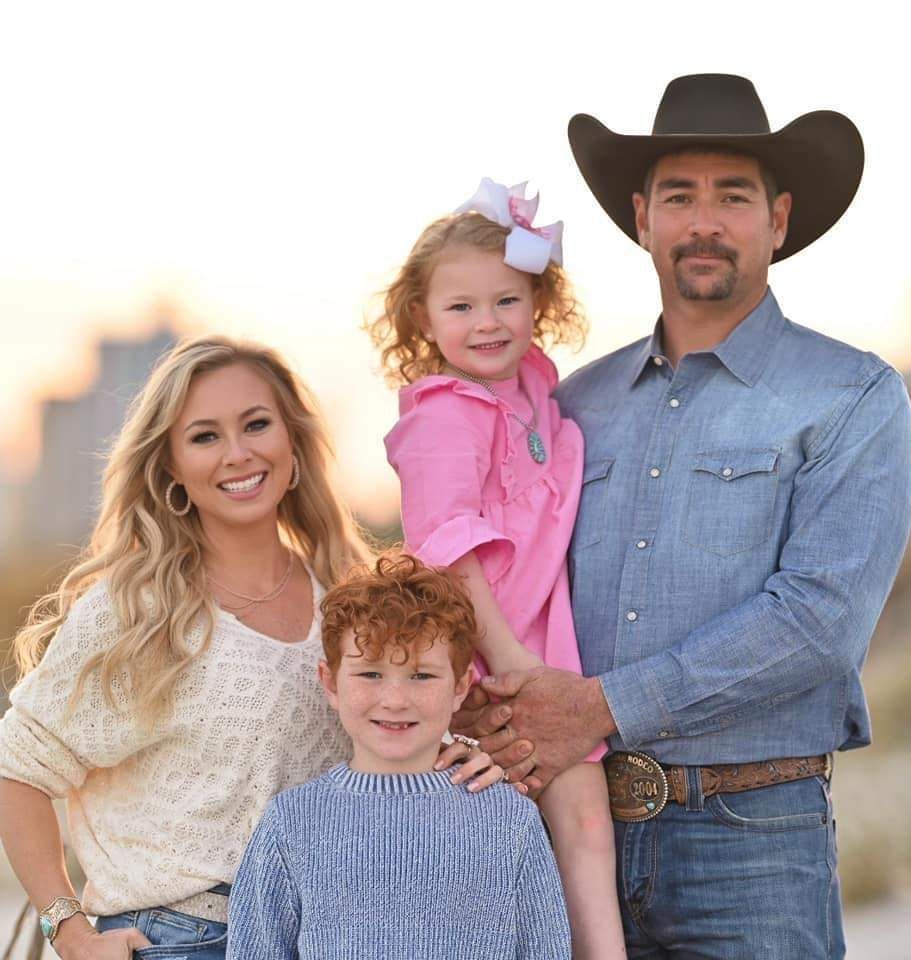 A man in a cowboy hat is posing for a picture with his family