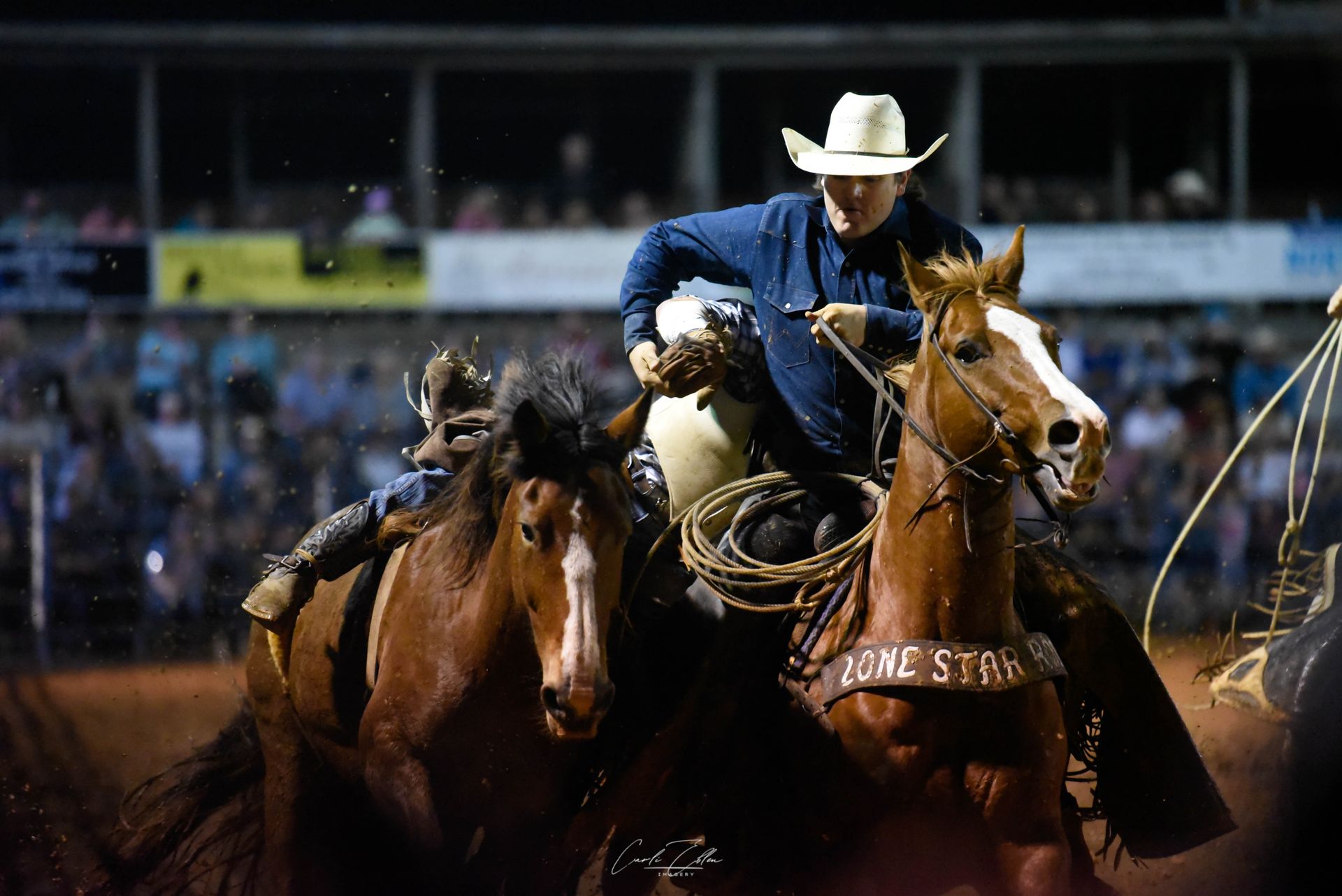 A man in a cowboy hat is riding a horse in a rodeo.