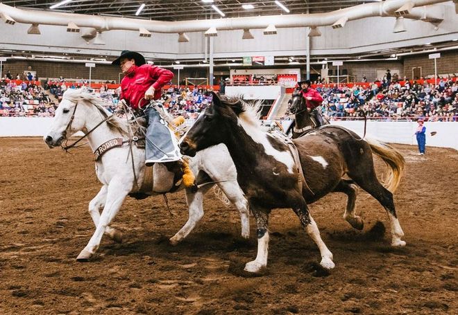 A man is riding a horse in a rodeo arena.