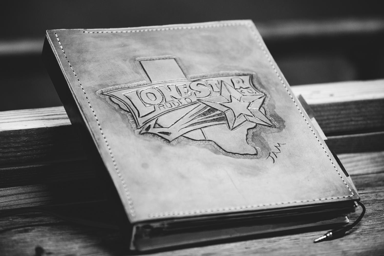 A black and white photo of a book sitting on a wooden table.