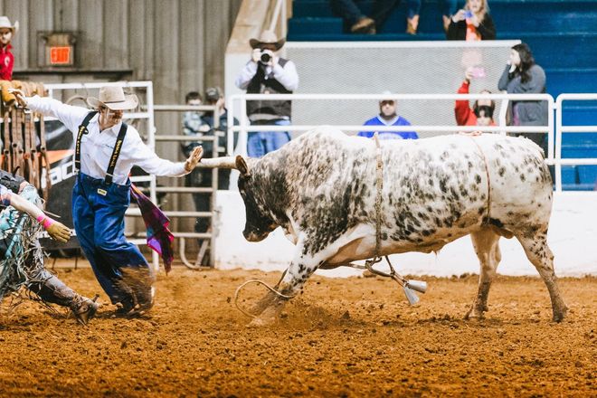 A man is riding a bull in a rodeo arena.