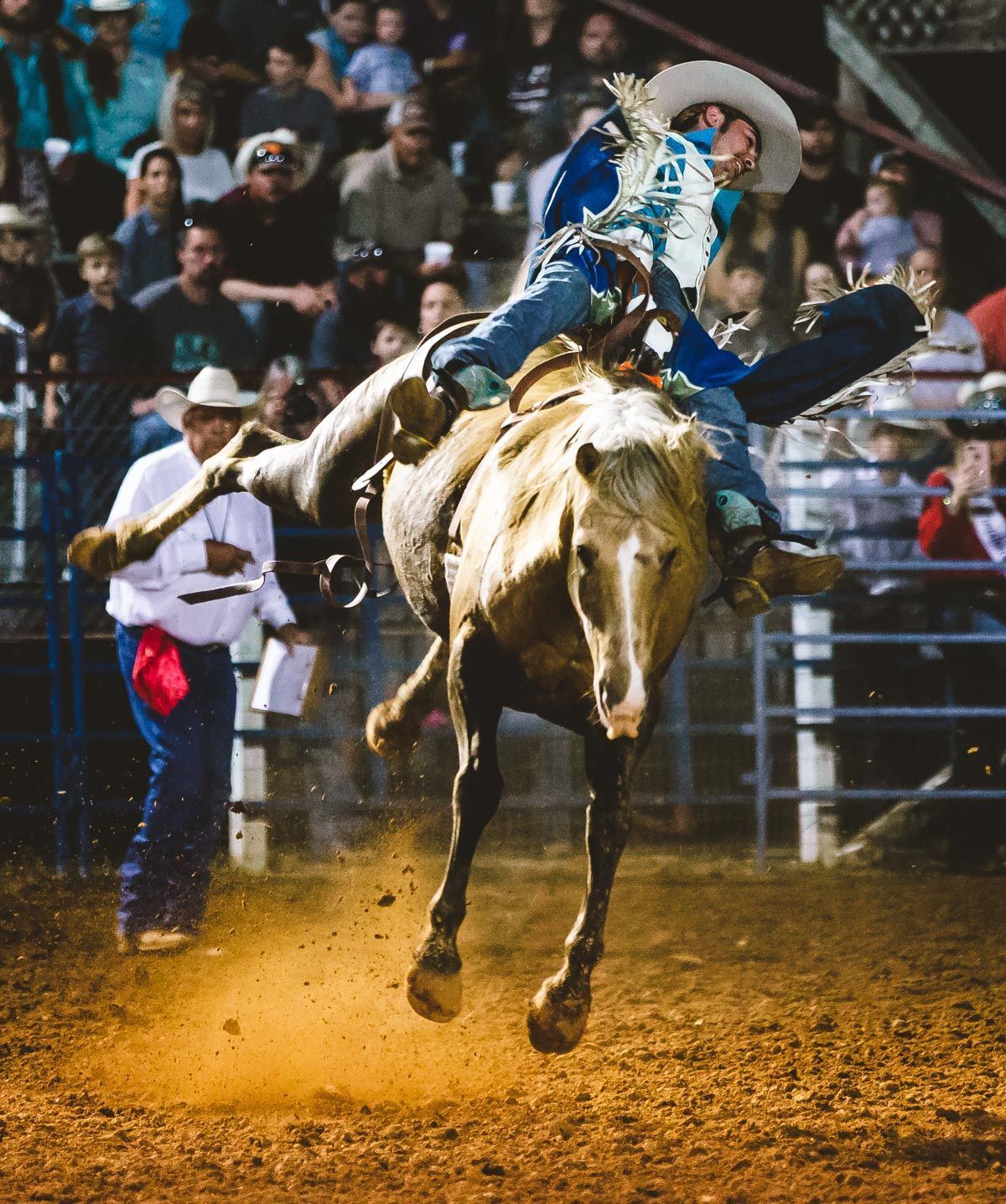 A man in a cowboy hat is riding a horse in a rodeo