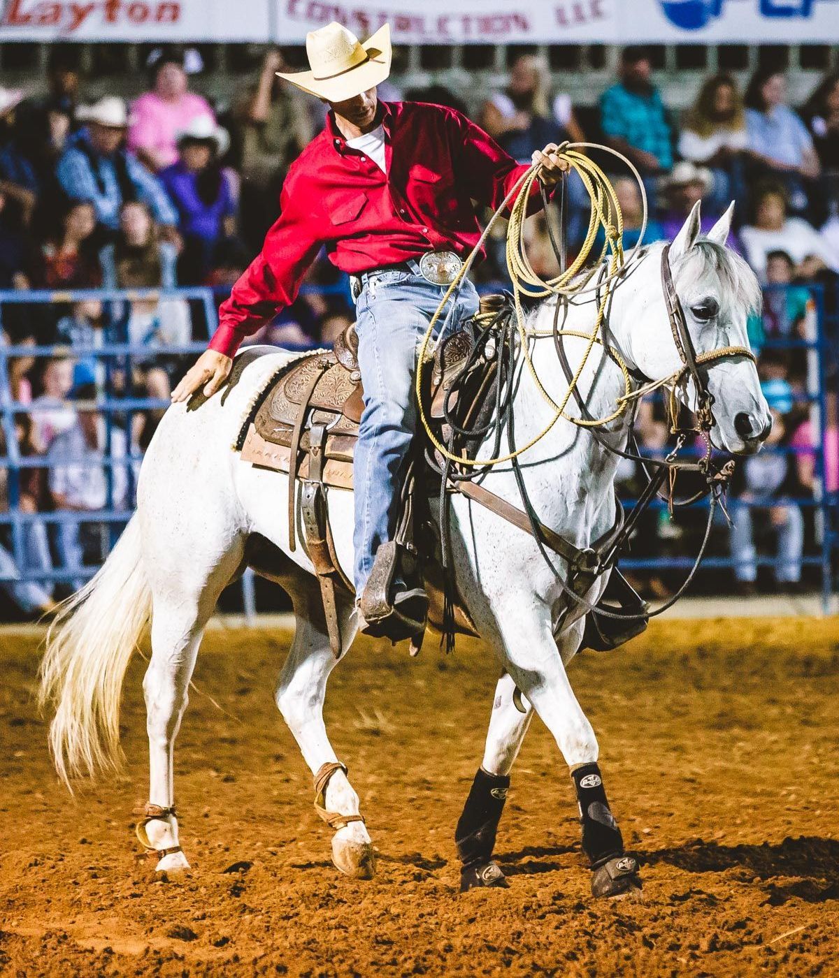 A man in a cowboy hat is riding a white horse.