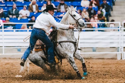 A man is riding a horse in a rodeo arena.