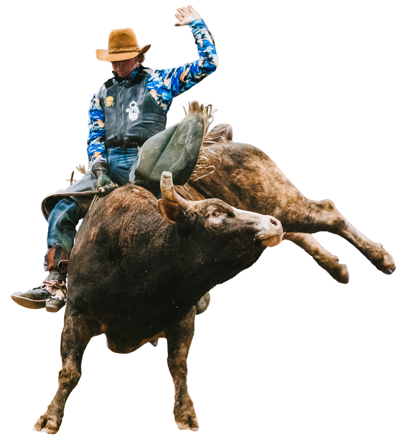 A man in a cowboy hat is riding a bull