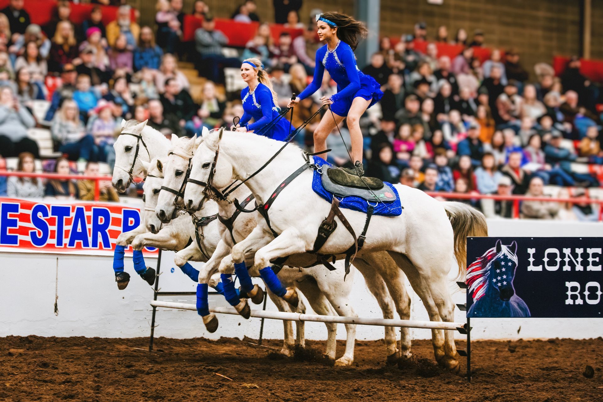 A group of people are riding horses in a rodeo arena.