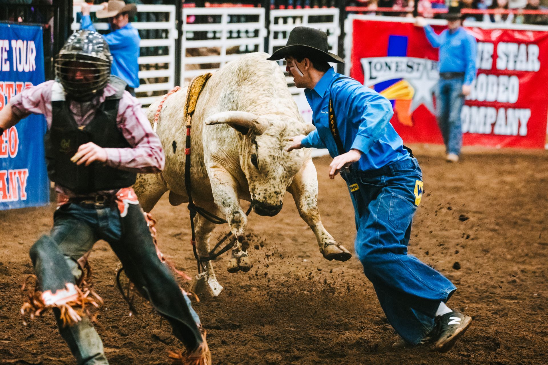 Two men are fighting a bull at a rodeo.