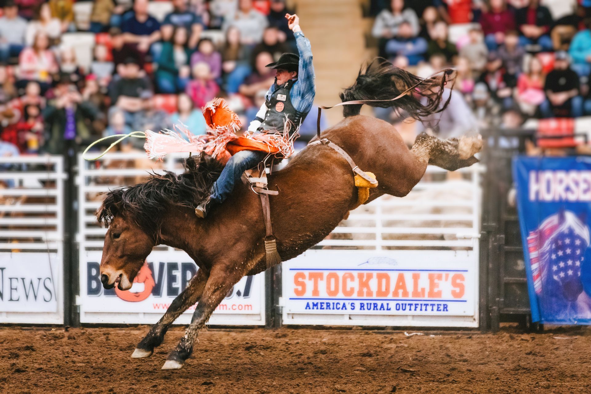 A man is riding a bucking horse at a rodeo.