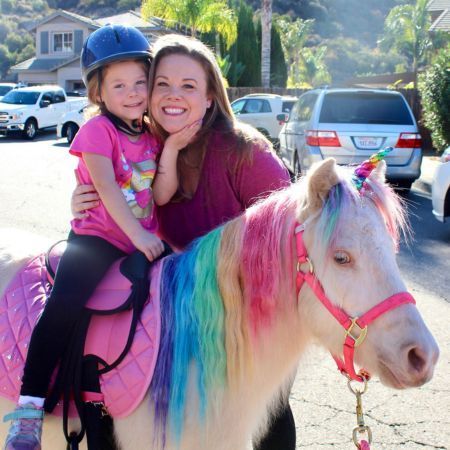Mommy & Daughter pose with a live rainbow unicorn at a unicorn birthday party in san diego