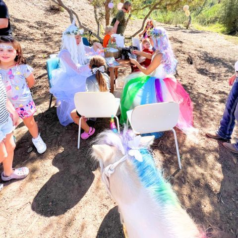 Unicorn princesses applying face makeup & jewels at a rainbow unicorn birthday party in san diego