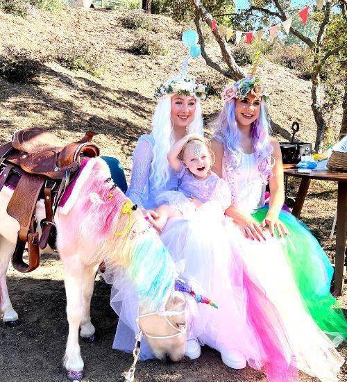 Two unicorn princesses posing for pictures at a rainbow unicorn kids birthday party in san diego