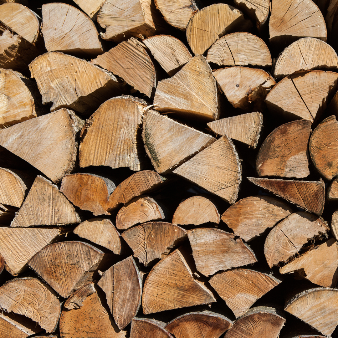 Pile of split firewood, showing exposed wood grain in various shapes and shades of brown.